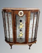 A 1950's walnut shaped display cabinet fitted with a clock