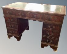 A reproduction mahogany twin pedestal writing desk fitted with nine drawers with green tooled