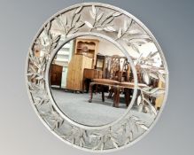 A contemporary circular framed wall mirror with foliage decoration