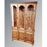 A contemporary pine display cabinet fitted with cupboards