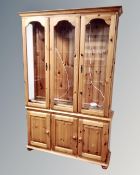 A contemporary pine display cabinet fitted with cupboards