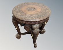 An Indian carved hardwood circular occasional table on elephant supports