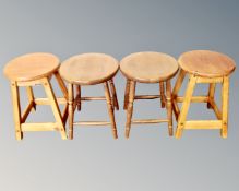 A pair of stained pine stools together with a further pair of rubber wood stools