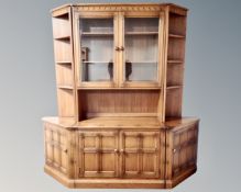 An Ercol elm and beech cocktail bookcase with pair of matching corner cabinets