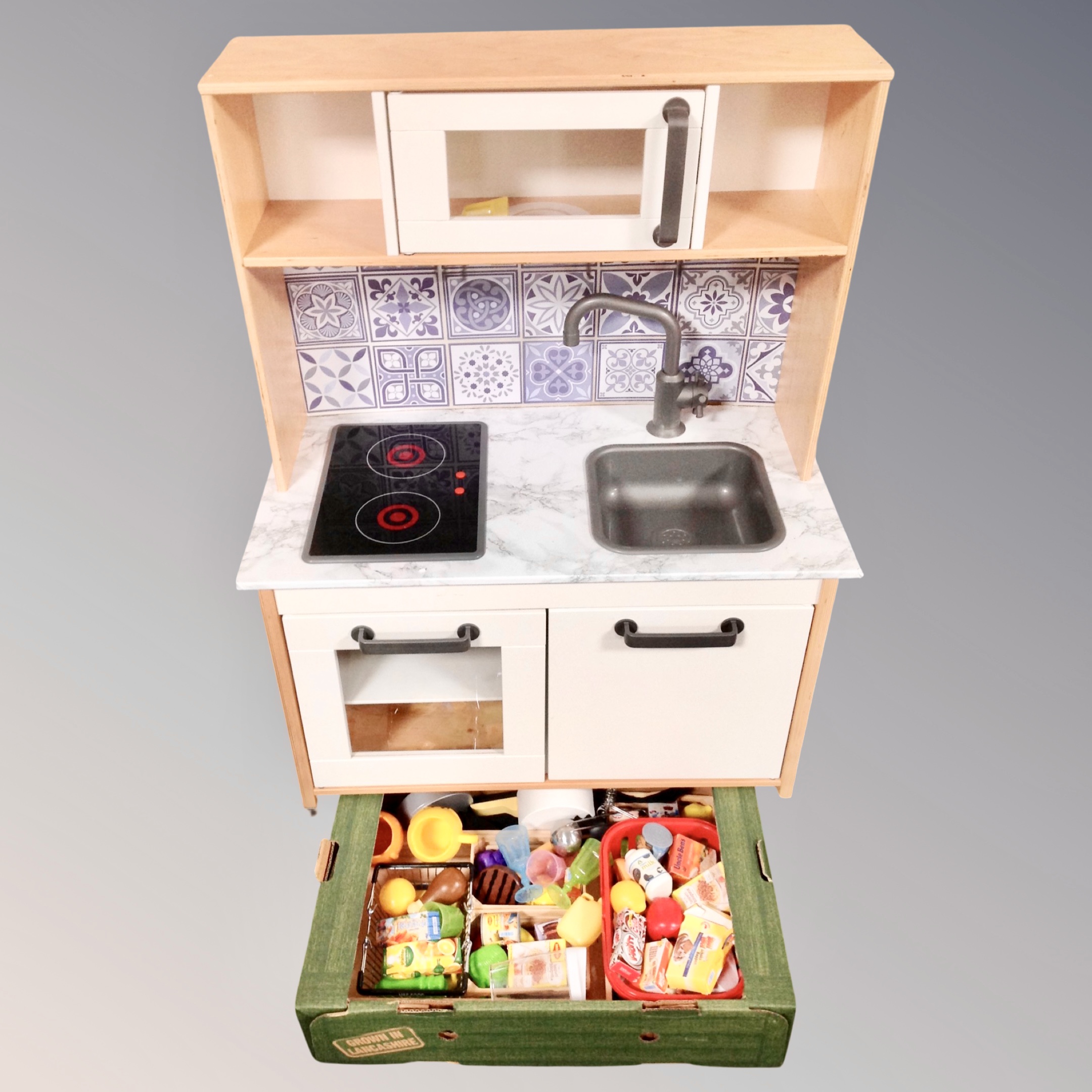 An IKEA play kitchen together with a box containing accessories.