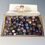 A wooden cigar box containing a quantity of antique and later glass marbles.