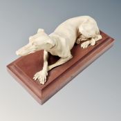 A composition figure of a greyhound resting on a wooden plinth, marked made in Great Britain.