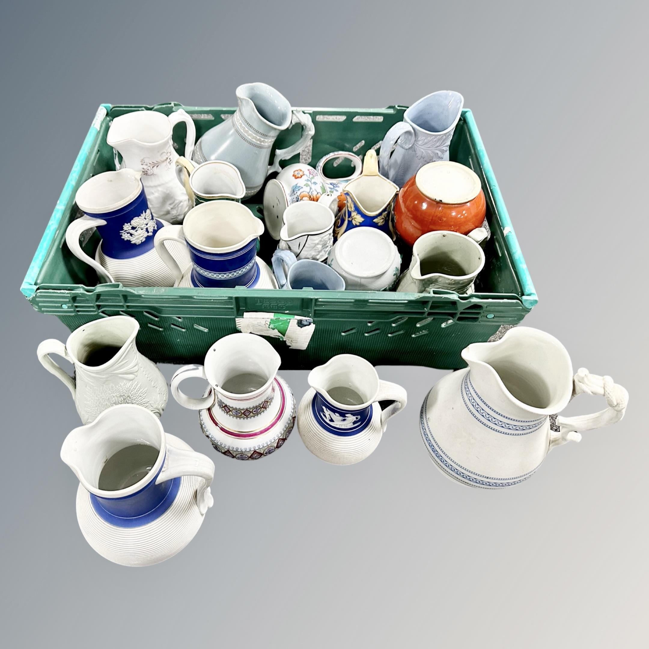 A crate containing a collection of antique and later jugs.