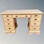 An Edwardian pine nine drawer twin pedestal desk with leather panel,