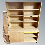 A continental light oak bookcase with cupboard sliding doors in base.