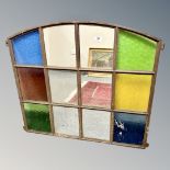 A cast iron window frame with multi-coloured glass, 88cm by 70cm.