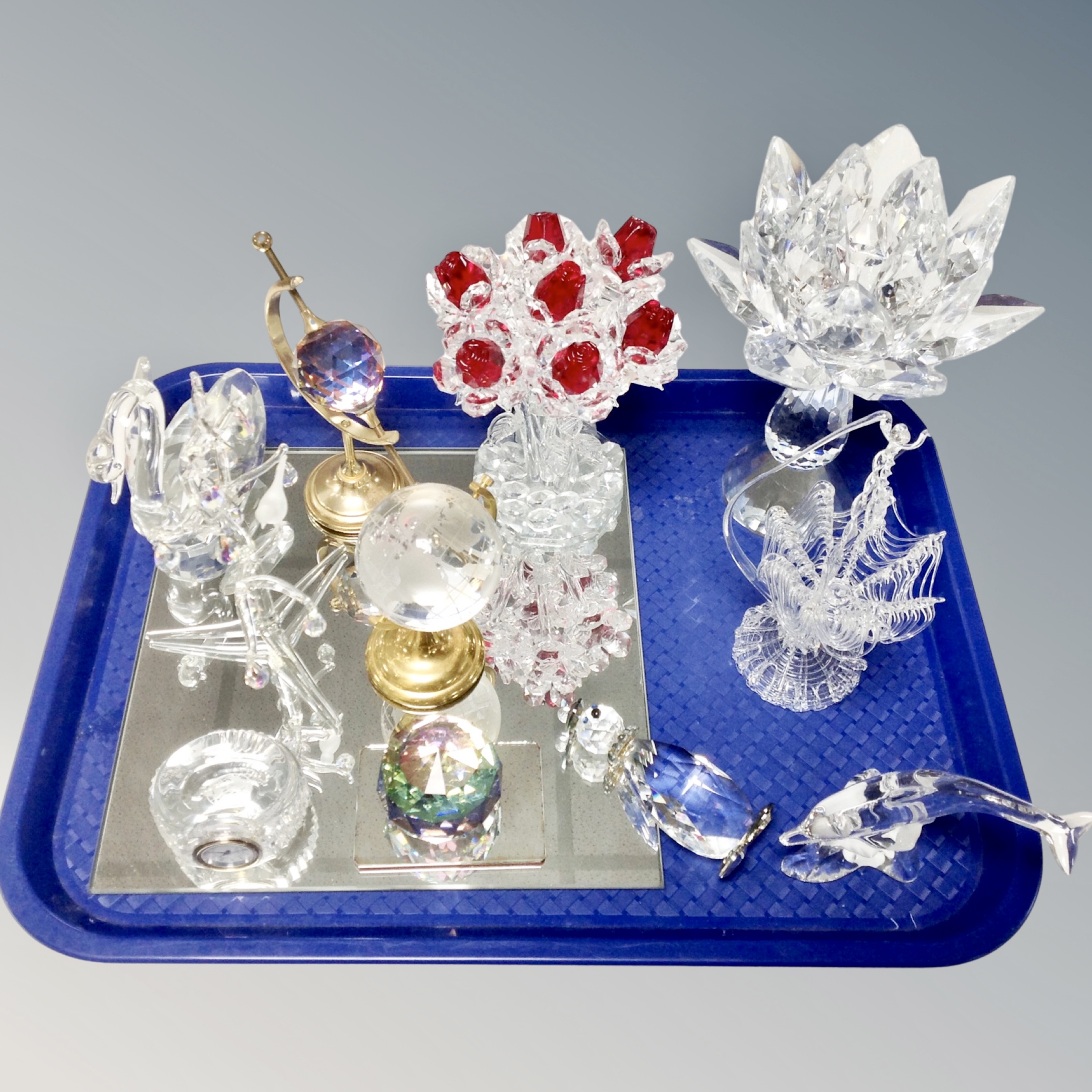 A tray containing assorted crystal ornaments and animal figures together with a mirrored stand.