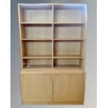 A light oak bookcase with cupboards in base.