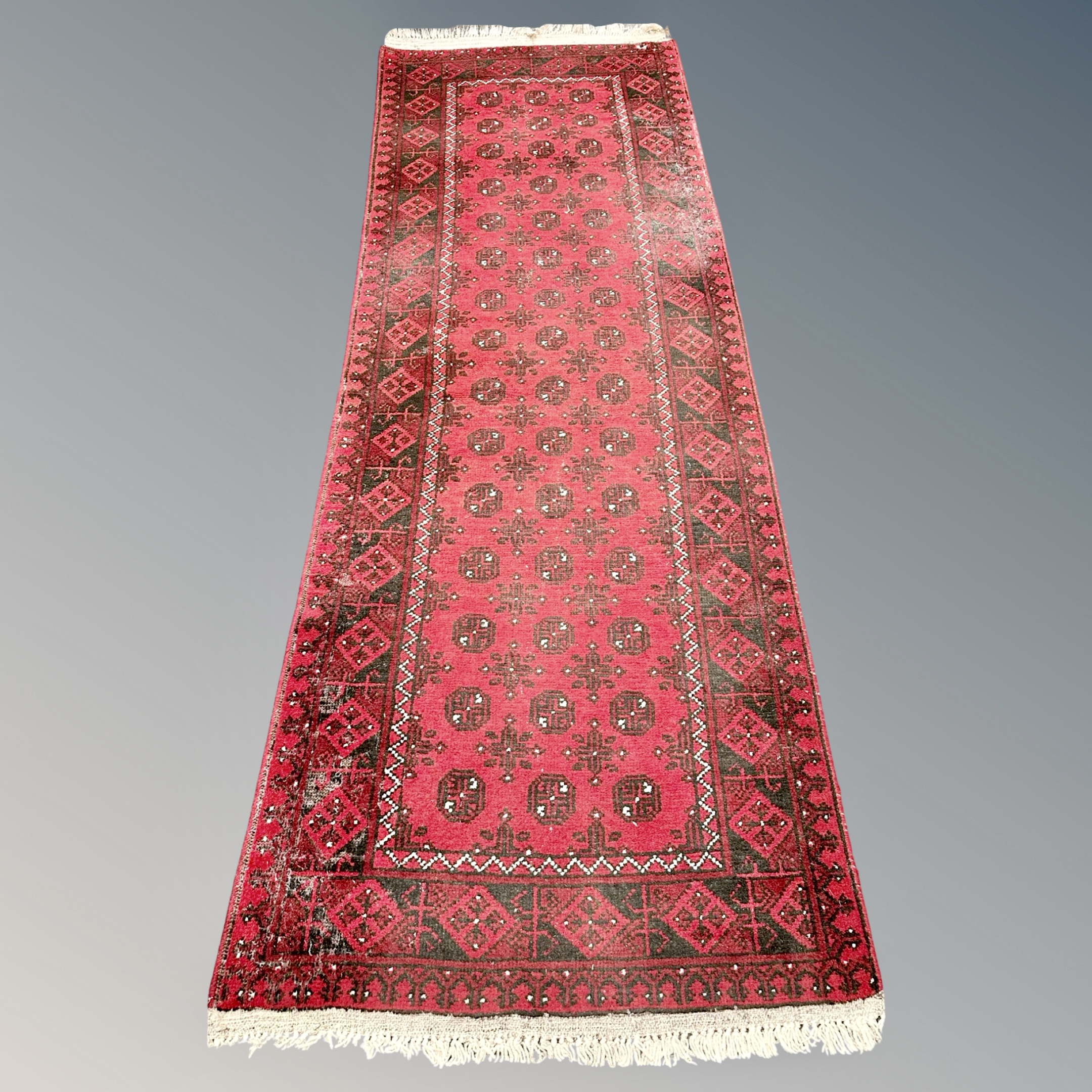 A Bokhara runner, Afghanistan, 100cm by 284cm. CONDITION REPORT: Wear to pile.