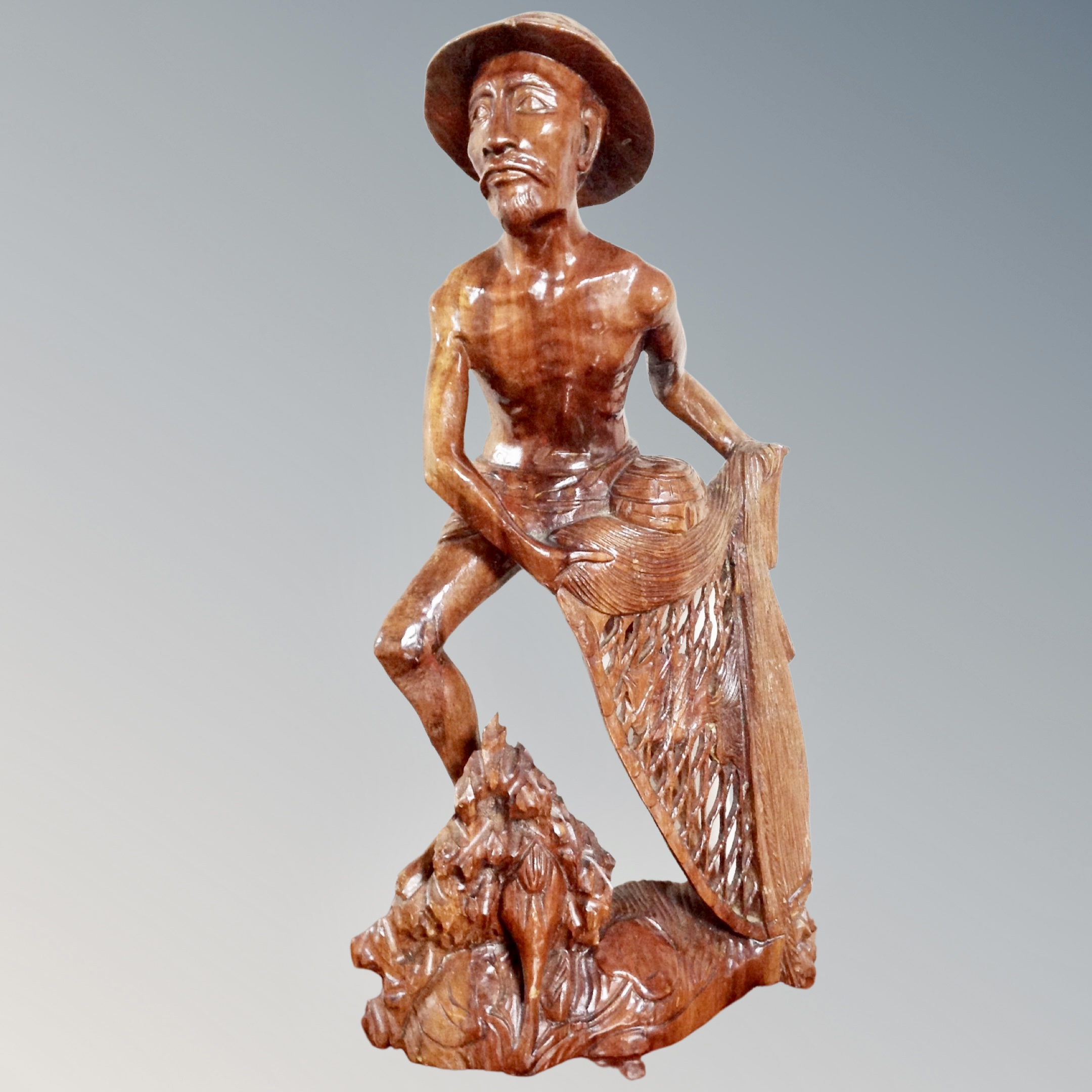 An Indonesian carved wooden figure of a fisherman.