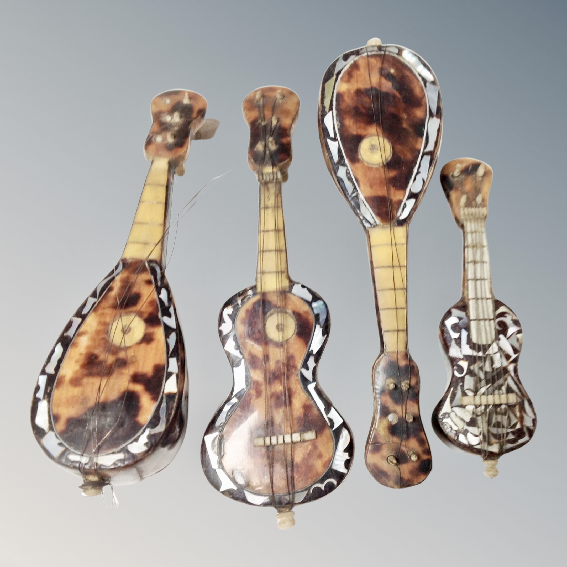 Four antique tortoiseshell miniature musical instruments with mother of pearl inlay.