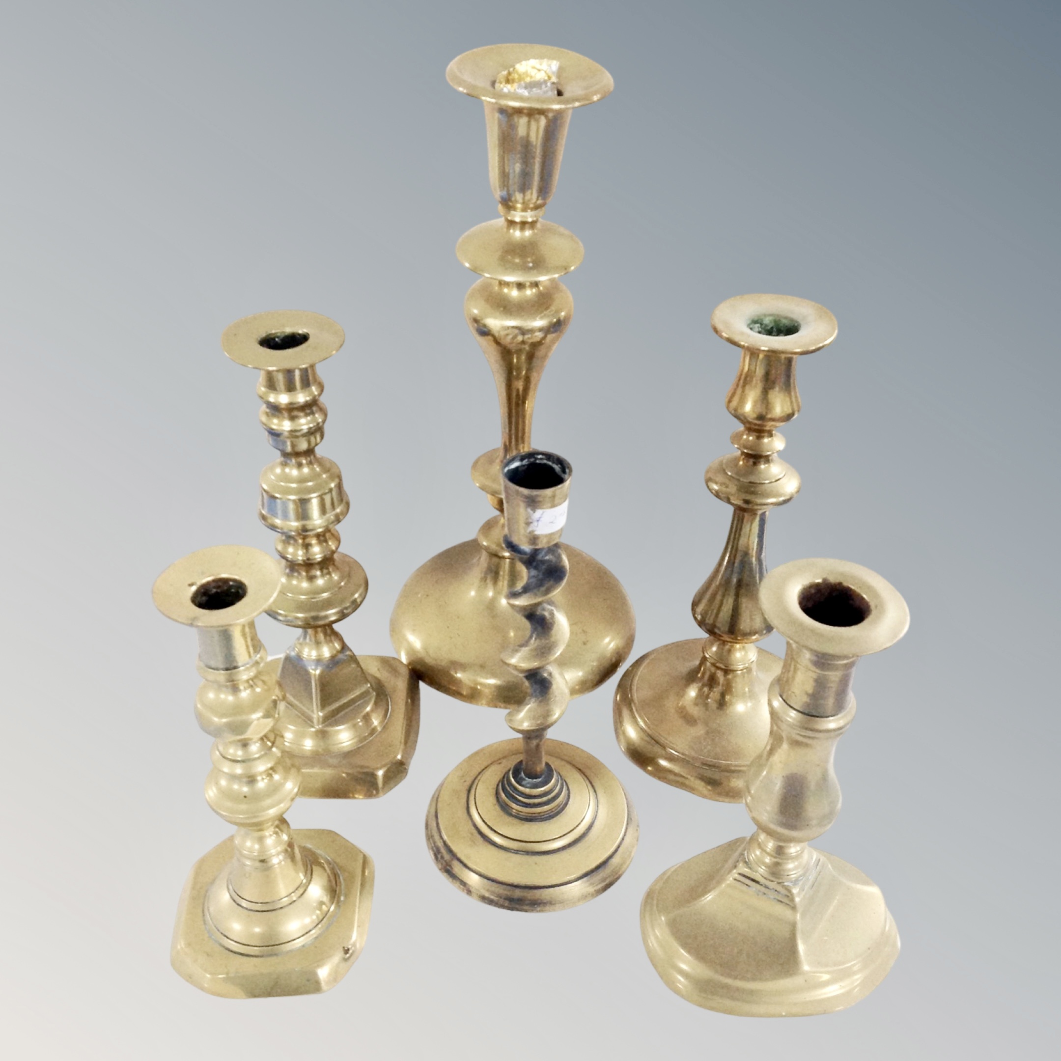 A tray containing six antique brass candlesticks.