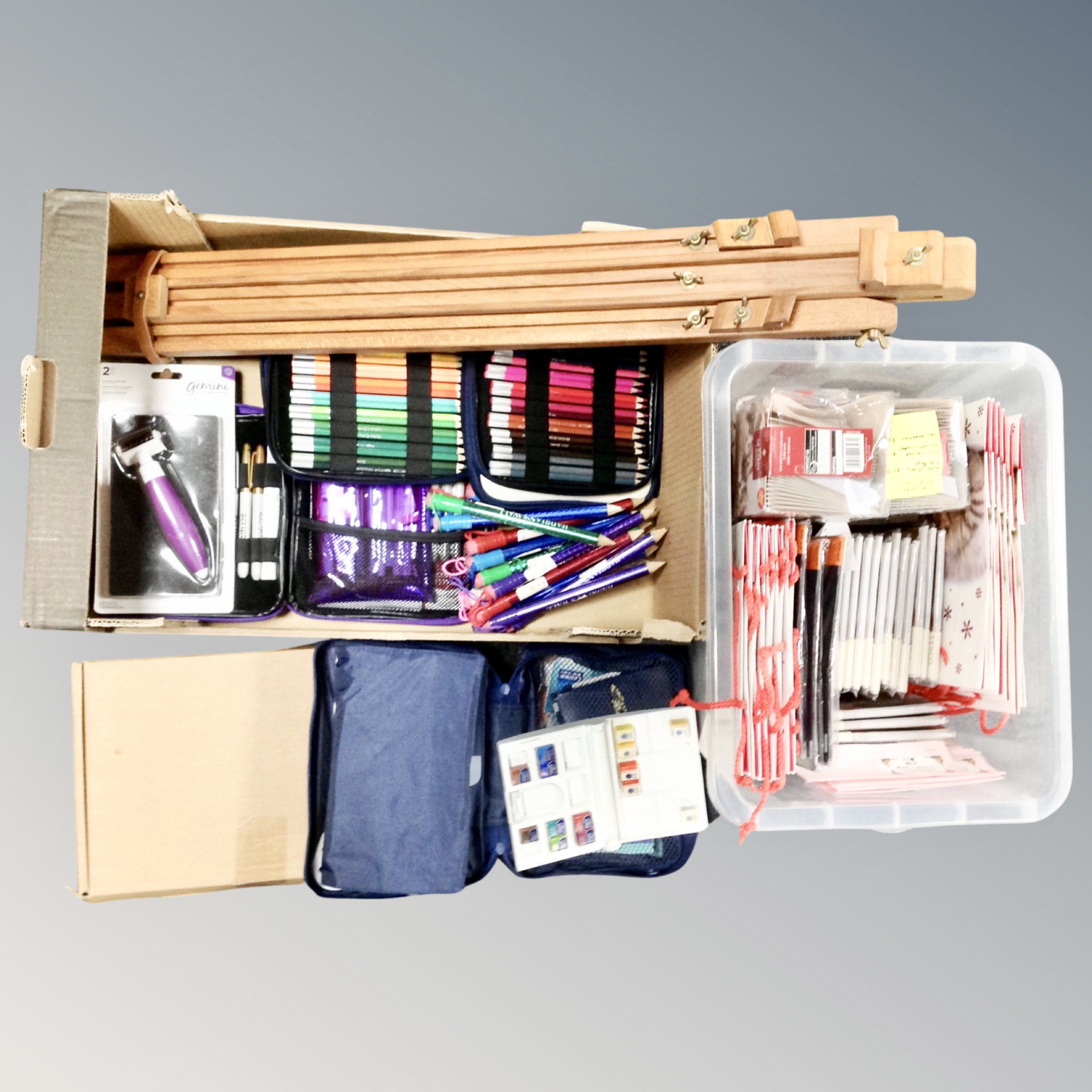 A box containing artist's supplies, easel, cased coloured pencils,