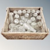 A vintage pine crate containing glass milk bottles
