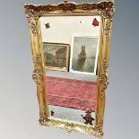 A mirror in ornate gilt frame, 54cm by 93cm.