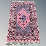 An Iranian/Caucasian rug, on pink ground, 182cm by 117cm.