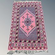 An Iranian/Caucasian rug, on pink ground, 182cm by 117cm.