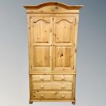 A Victorian style pine double door hanging wardrobe fitted with four drawers beneath.