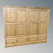 A contemporary pine four door wardrobe fitted with four drawers beneath,