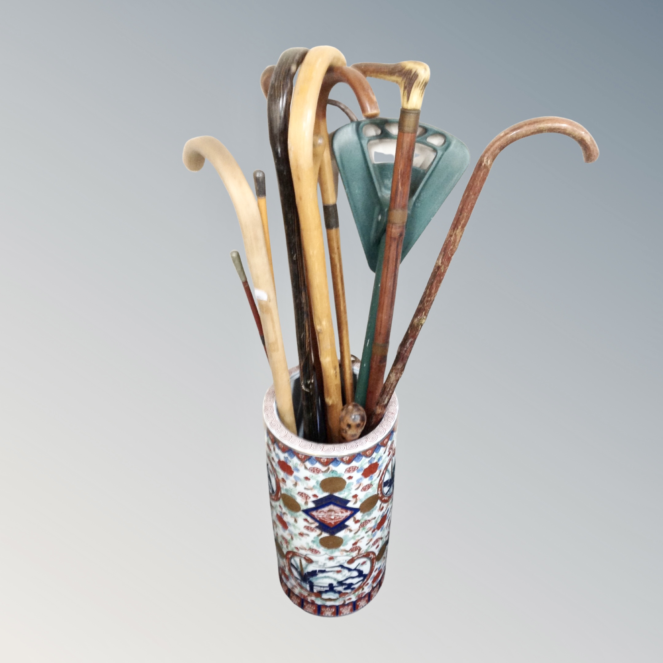 An Oriental style cylindrical stick pot containing a quantity of sticks, a shooting stick etc.