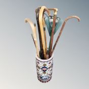 An Oriental style cylindrical stick pot containing a quantity of sticks, a shooting stick etc.