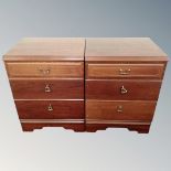 A pair of three drawer bedside chests in a mahogany finish.