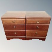 A pair of three drawer bedside chests in a mahogany finish.