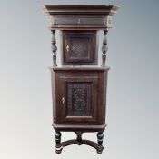 An early 20th century heavily carved double door corner cabinet on stand.