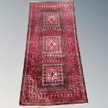 An Afghan long rug on red ground, 205cm by 100cm.