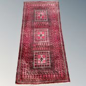 An Afghan long rug on red ground, 205cm by 100cm.