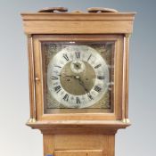 A Scandinavian oak longcase clock with brass and silvered dial, pendulum and weights.