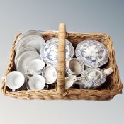 A vintage wicker basket with handle containing eight pieces of Old Chelsea blue and white tea and