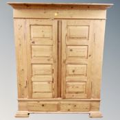 An antique pine double door wardrobe fitted with two drawers.
