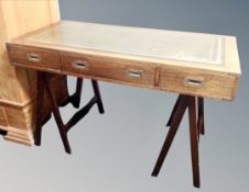 A campaign style writing table with a green leather inset panel, brass handles and mounts,