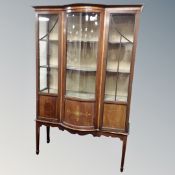 A late Victorian inlaid mahogany glazed display cabinet on raised legs.