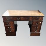 A reproduction twin pedestal writing desk fitted with nine drawers and a tooled leather inset panel.