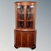 A reproduction mahogany bow fronted double door glazed corner cabinet fitted with cupboards below.