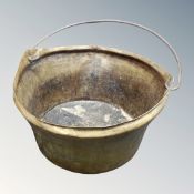 A 19th century brass cast iron handled cooking pot on raised feet.