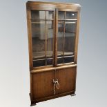 A 1930s oak double door bookcase fitted with cupboards below.