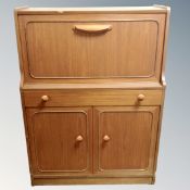 A mid-20th century teak finish fall front writing bureau fitted with double door cupboard and