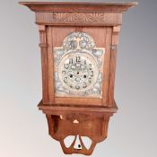 An oak cased wall clock with a silvered Art Nouveau dial.