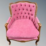 A continental carved beech framed armchair upholstered in a vivid pink buttoned back fabric.