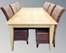 A contemporary extending dining table with two leaves in an oak finish with a set of eight wicker