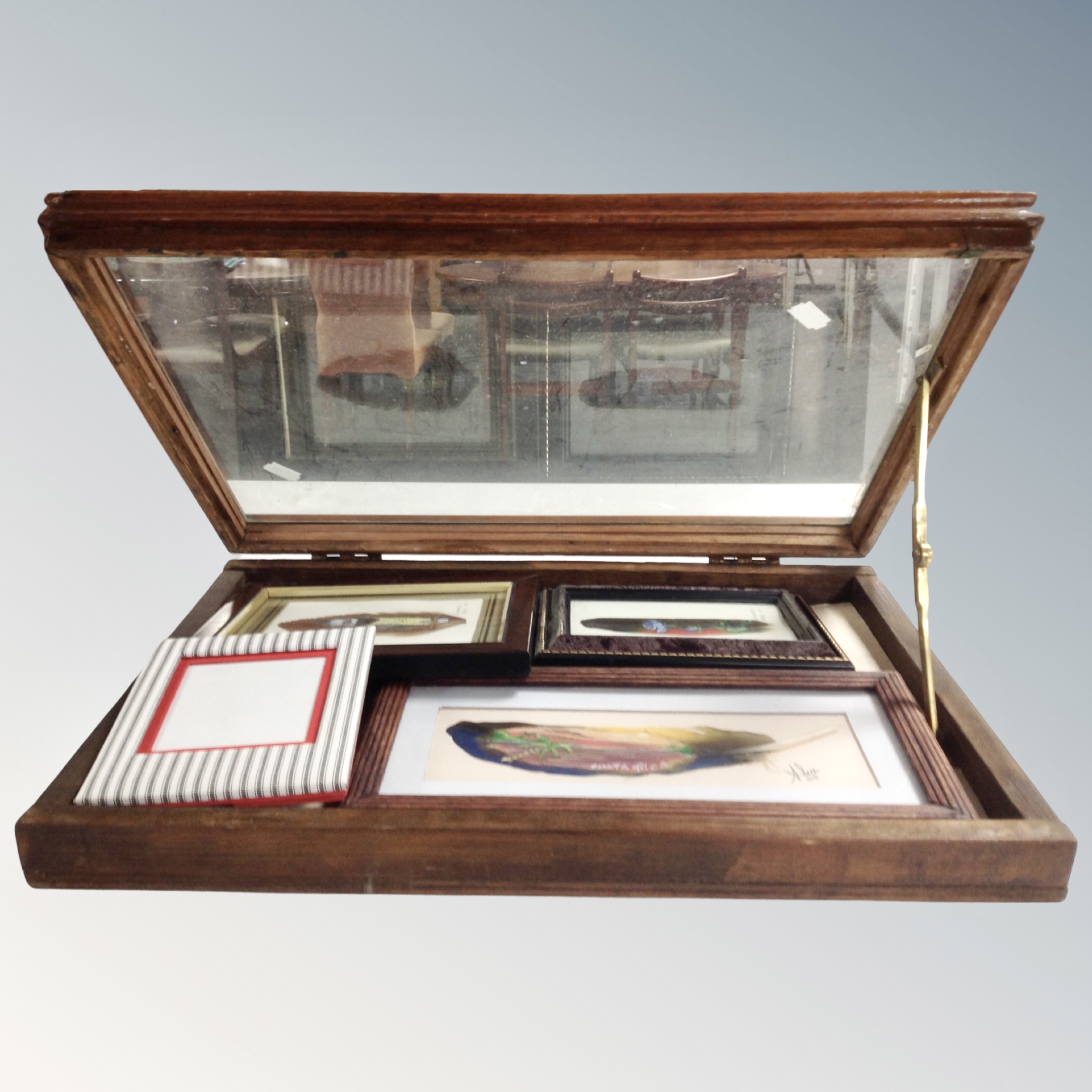 A glazed mahogany tabletop cabinet containing hand painted feathers, tourist items in cases etc.