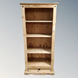 A set of pine open bookshelves fitted with a drawer beneath.